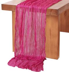 a table with a pink scarf on top of it and a wooden bench in the background