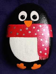 a painted rock with a penguin wearing a scarf