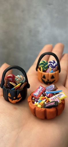 three miniature pumpkins with candy in them sitting on someone's hand and one is holding it