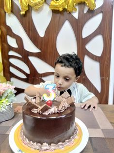 a young boy sitting in front of a chocolate cake with the number five on it