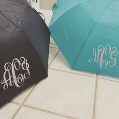 two umbrellas with monogrammed initials on them sitting on the floor next to each other