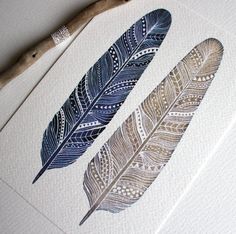 two blue and white feathers sitting on top of a piece of paper