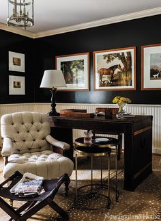 a living room with black walls and pictures on the wall, including a white chair