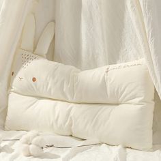 a bed with white sheets and pillows on top of it in front of a curtain