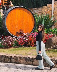 a woman walking down the street in front of a wooden barrel