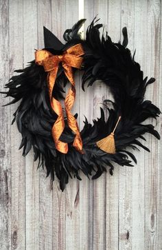 a black wreath with orange ribbons hanging on a wooden fence next to a white door