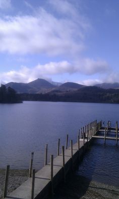 a dock on the water with mountains in the background