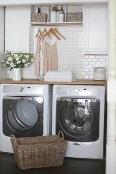 a washer and dryer in a small room with white tile on the walls