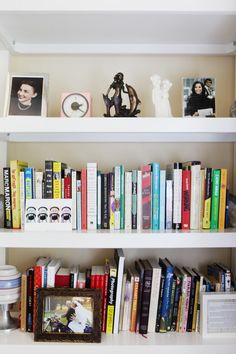 a book shelf filled with lots of books next to a clock and other items on top of it