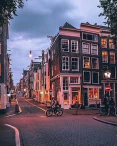 a city street with several buildings and motorcycles parked on the side of the road at night