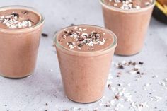 three glasses filled with chocolate smoothie on top of a table