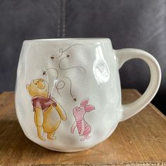 a winnie the pooh mug sitting on top of a wooden table