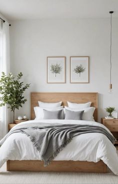 a bed with white sheets and pillows in a bedroom next to two plants on either side of the bed