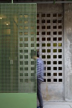 a man walking past a green and white wall with squares on it's side