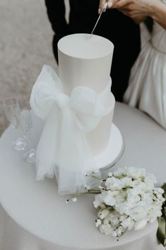 the bride and groom are cutting into their wedding cake with white flowers on the table