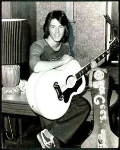 a black and white photo of a woman sitting on a table with a guitar in front of her