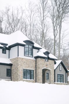 a house with snow on the ground and trees in the backgroung area