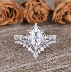 a close up of a ring on a wooden table with roses in the back ground