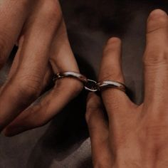 two hands with rings on their fingers, one holding the other's hand and the other