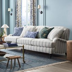 a living room with blue walls and striped furniture in the corner, along with two lamps