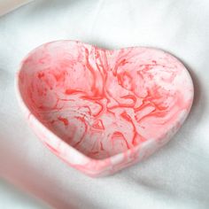 a heart shaped bowl sitting on top of a white sheet