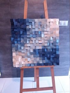 an easel with a painting made out of blocks of blue and brown paper on it