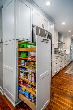 an organized pantry in the middle of a kitchen with white cabinets and wood flooring