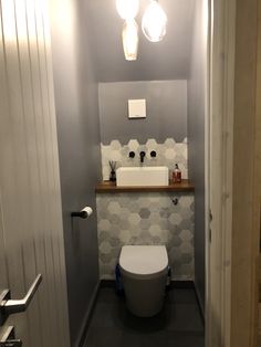 a white toilet sitting in a bathroom next to a sink and light bulb above it