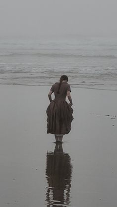 a woman in a dress walking on the beach