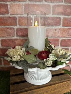 a white vase with flowers and a lit candle