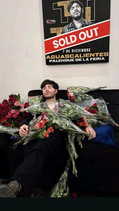 a man sitting on top of a couch holding flowers