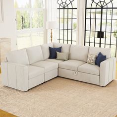 a living room with a large white couch and rug on the floor in front of windows