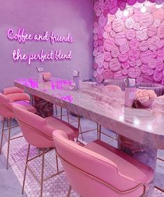 a dining table with pink chairs in front of a purple wall that says coffee and friends the perfect blend