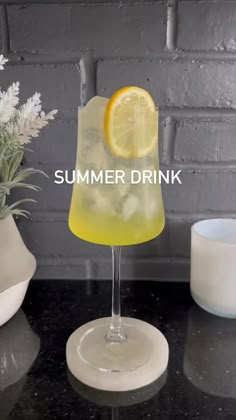 a glass filled with lemonade sitting on top of a table next to a vase