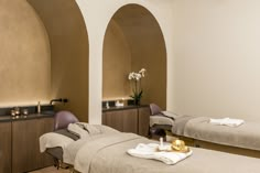 a couple of beds sitting next to each other in a room with arches on the wall