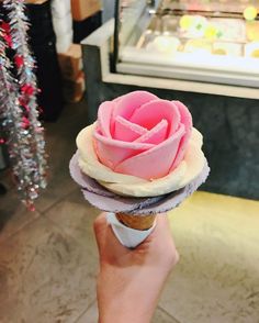 a person holding up a cupcake shaped like a rose