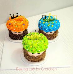 three decorated cupcakes sitting on top of a white table