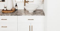 a bathroom with marble counter tops and gold faucet