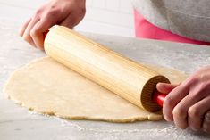 a person rolling out dough on top of a floured surface with a rolling pin