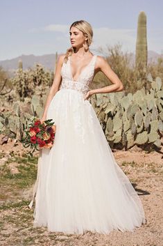 a woman standing in front of a cactus wearing a wedding dress