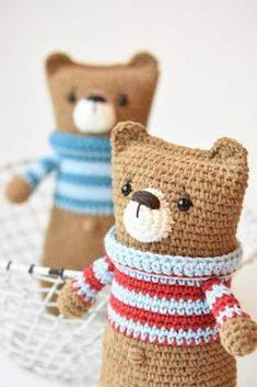 two crocheted teddy bears wearing sweaters and holding tennis racquets