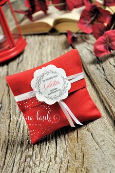 a red envelope with a white ribbon on top of a wooden table next to flowers