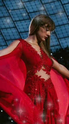 a woman in a red dress is standing with her hands on her hips and looking down