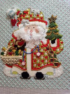 a cross stitch santa clause holding a basket