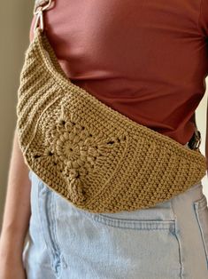 a woman is wearing a crocheted bag with an attached shoulder strap and has her hands in the pocket