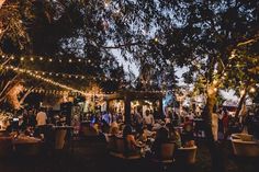 people are sitting at tables under string lights in the evening, and there is no image here to provide a caption for