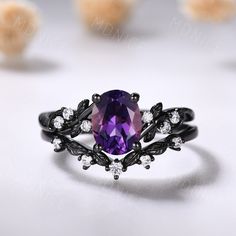 a ring with an amethyst purple stone surrounded by white and black diamonds on a table