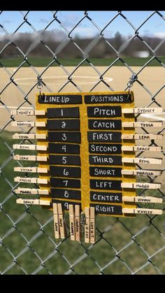 a baseball field behind a chain link fence with bats hanging on it's side