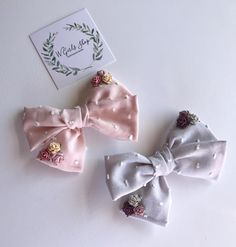 three small bows with flowers on them sitting next to a card and some other items