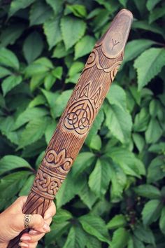 a person holding a wooden object in their hand with intricate designs on the outside of it